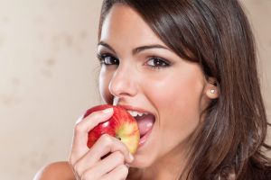 Smiling young woman eating an apple