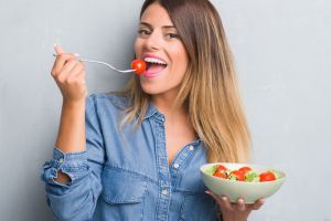 Smiling young woman eating a healthy fruit salad
